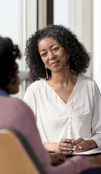 The mature adult female therapist listens compassionately to the unrecognizable female client share her problems.