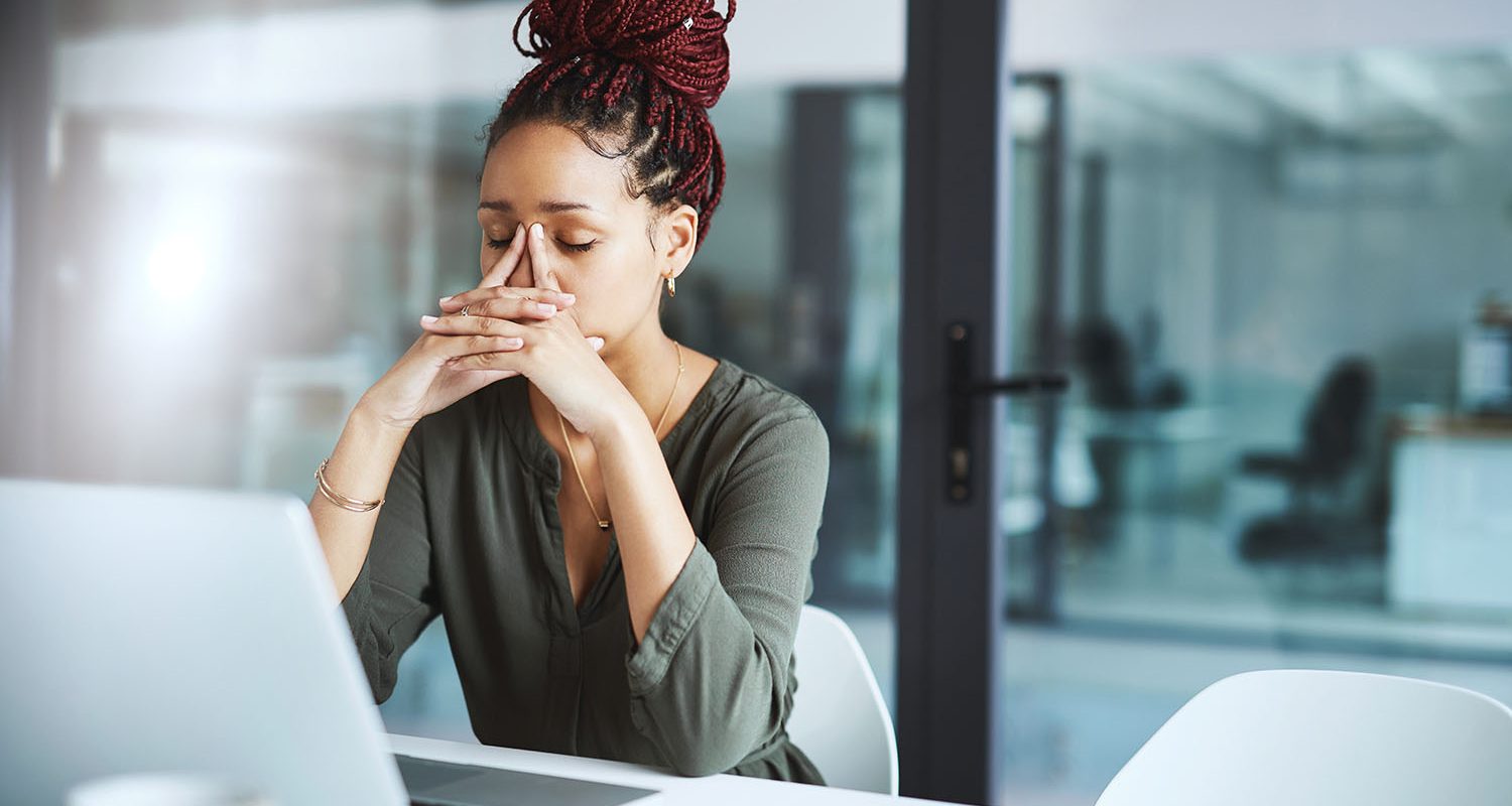 Shot of a young businesswoman looking stressed out while working in an office