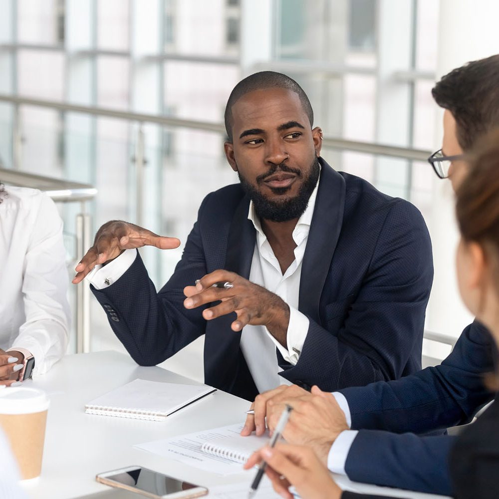 Black millennial boss leading corporate team during briefing in boardroom Millennial employees gathered in boardroom for training, black boss ceo leader leading corporate team during seminar learning at modern office. Internship and leadership coaching and education concept
