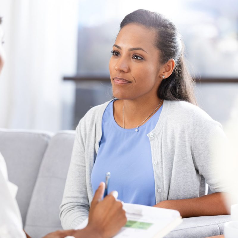 A mid adult female client is upset, uncomfortable, and possibly angry with the questions the unrecognizable female therapist asks.