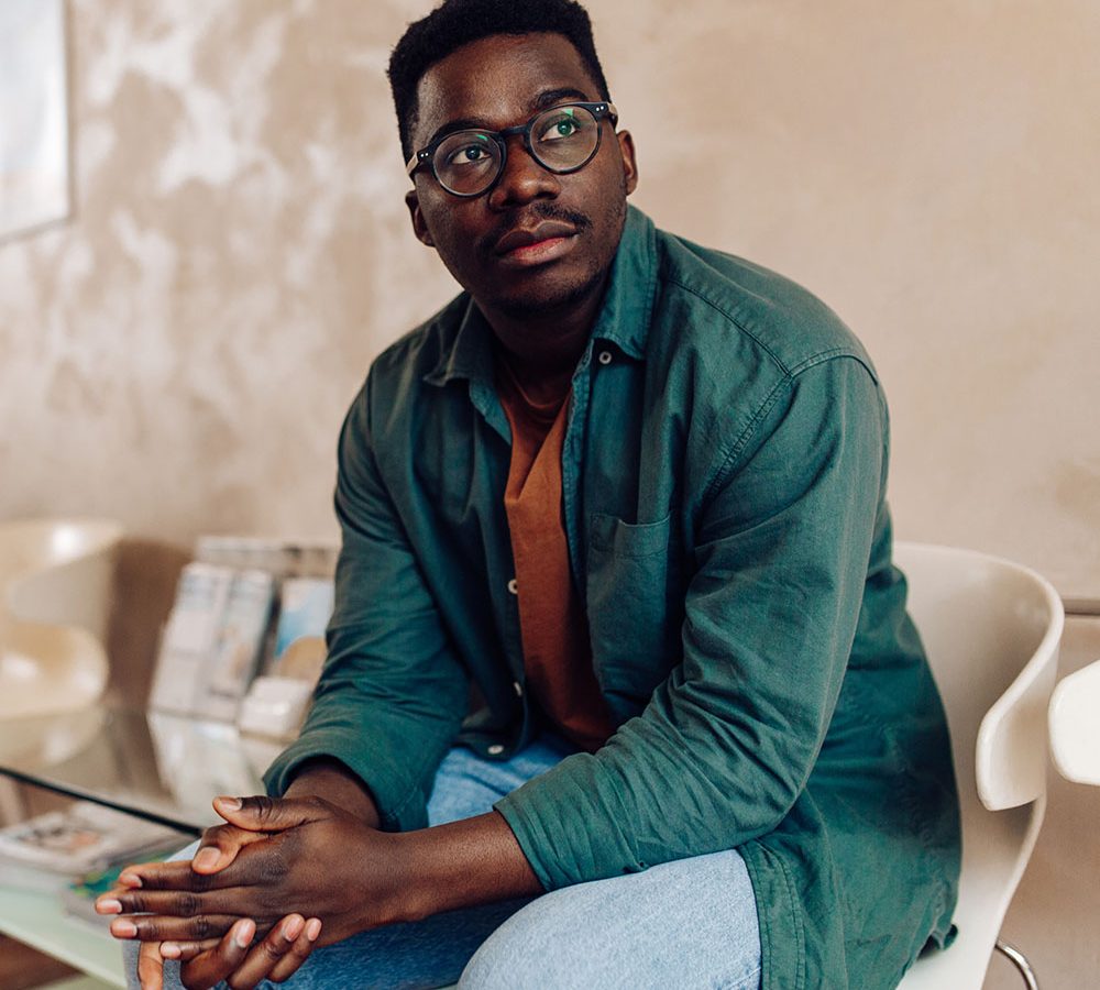 African American patient sitting in the waiting room at the hospital and worrying for his health.