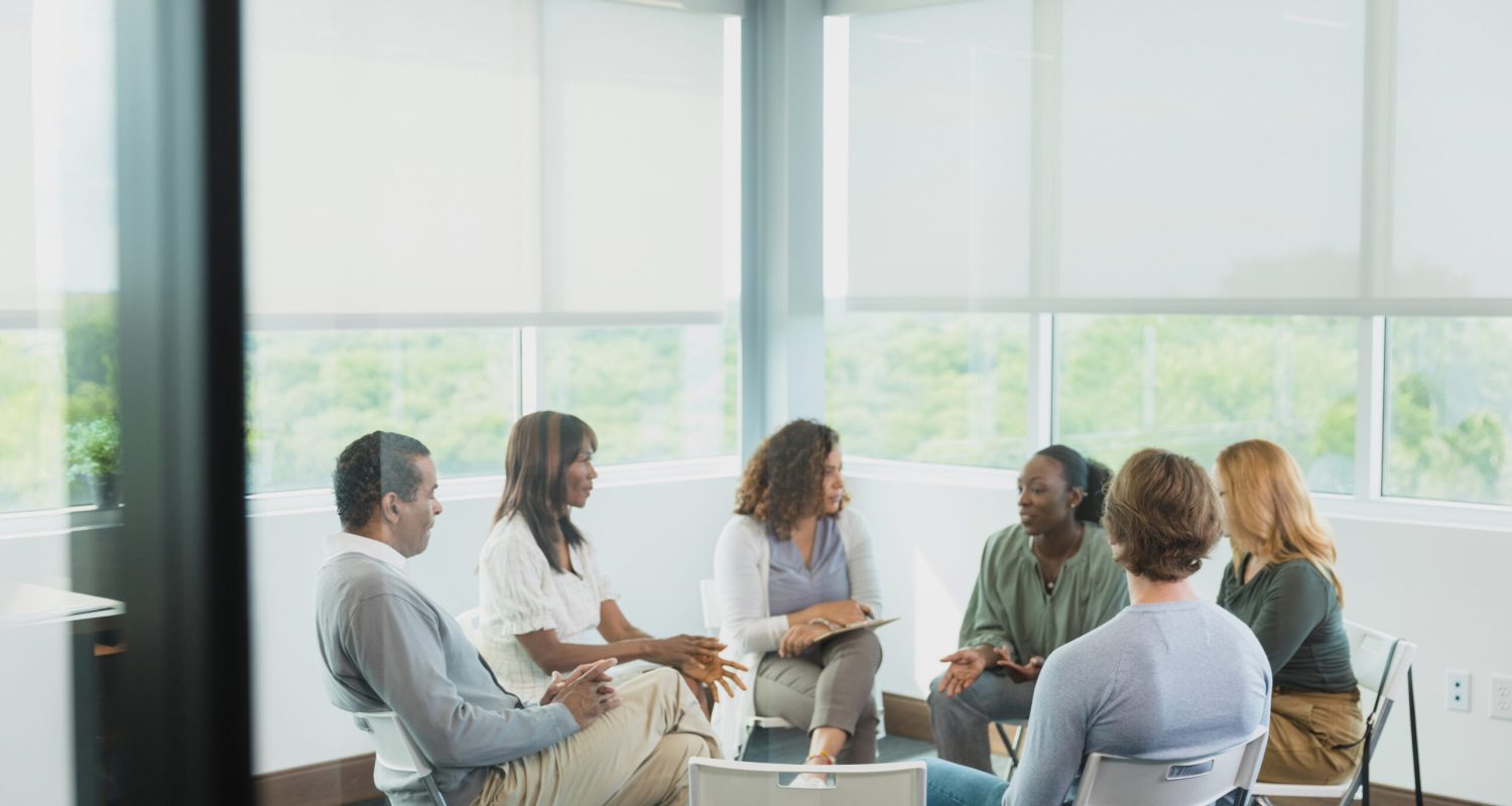 Diverse men and women meet for a focus group.  They are sitting in a circle in their place of work.