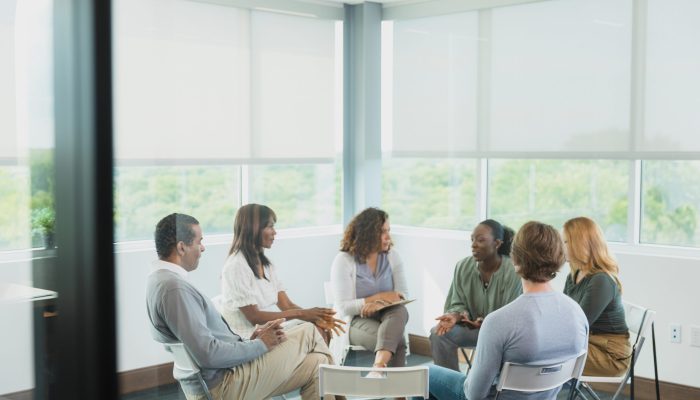 Diverse men and women meet for a focus group.  They are sitting in a circle in their place of work.