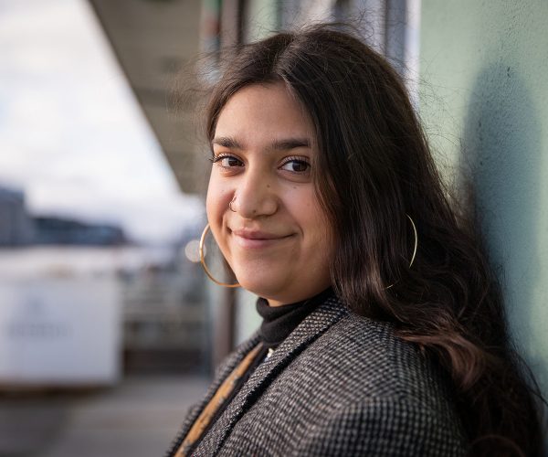 Portrait of a smiling young girl. Happy and calm teenage female is leaning with her back against a wall. Beautiful North African girl. Happy youth concept