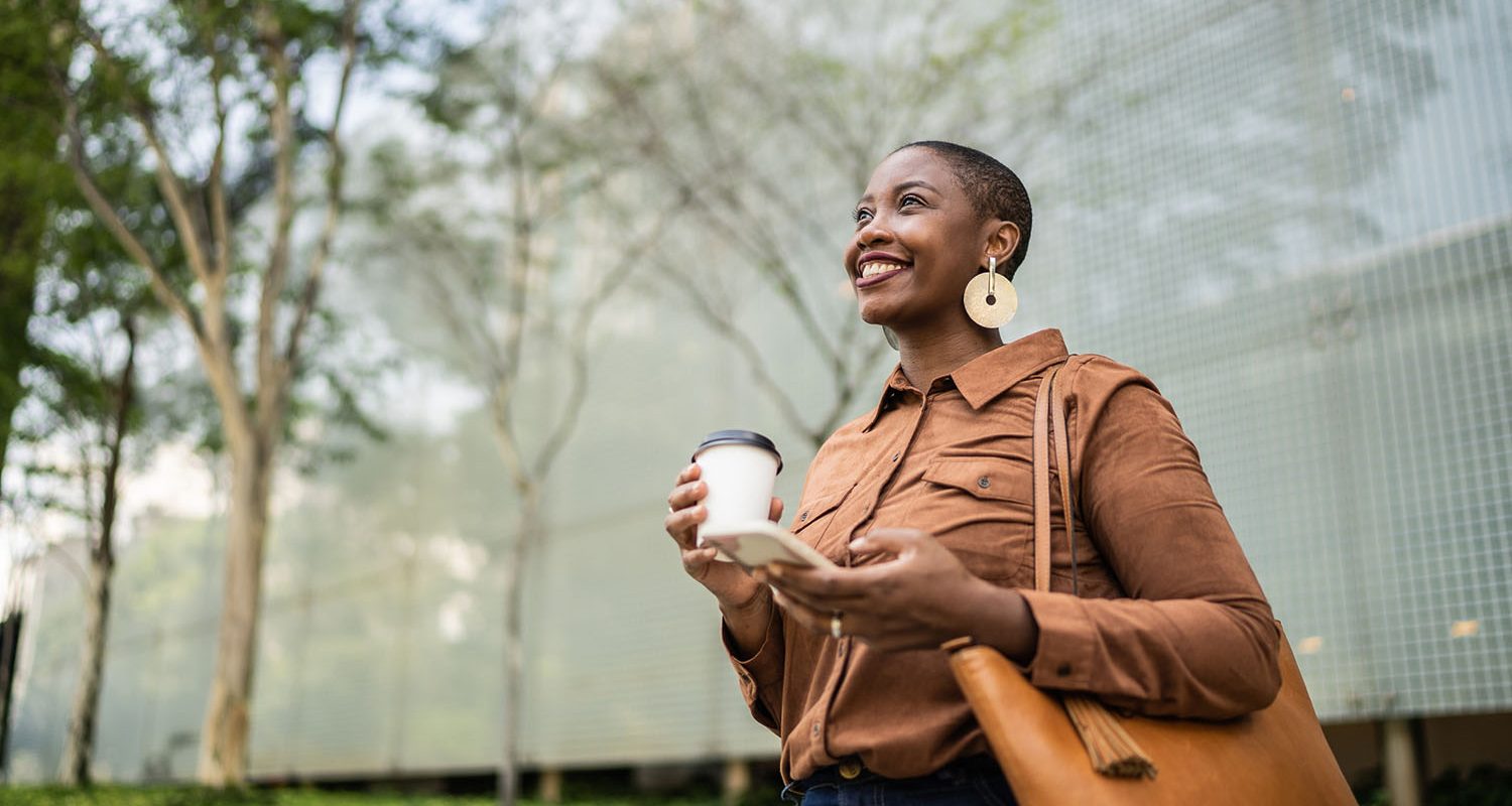 Business woman holding smartphone and looking away outdoors