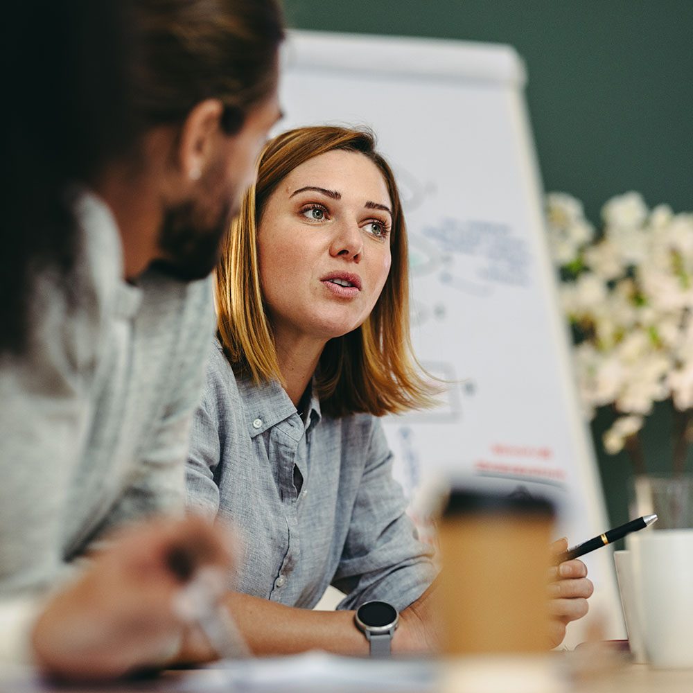 Young businesswoman having a discussion with her colleagues in a boardroom. Creative young businesswoman sharing her ideas during a meeting in a modern office.