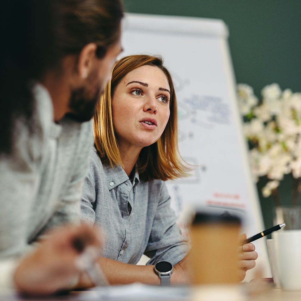 Young businesswoman having a discussion with her colleagues in a meeting Young businesswoman having a discussion with her colleagues in a boardroom. Creative young businesswoman sharing her ideas during a meeting in a modern office.