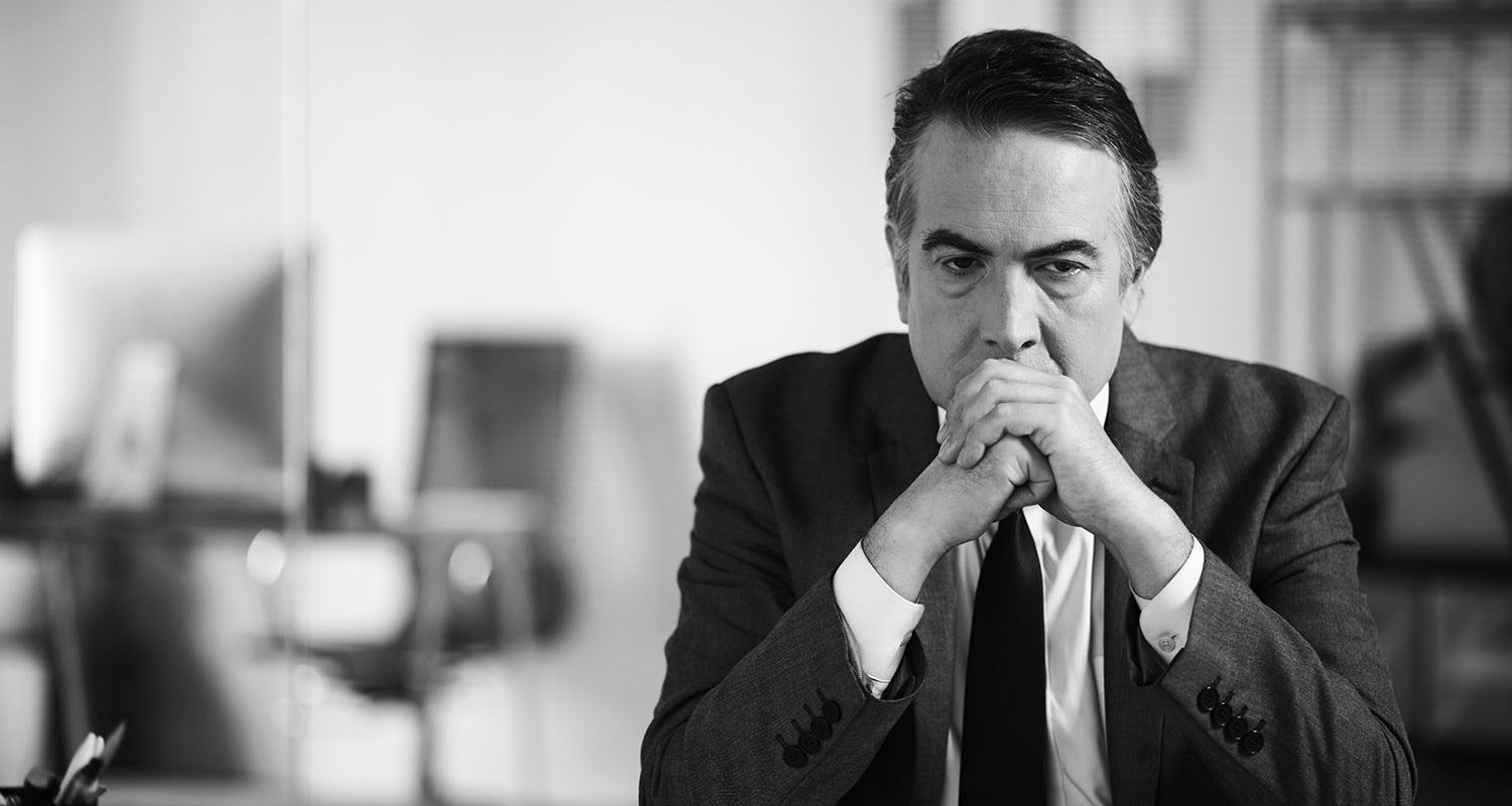 Portrait of stressed tired lawyer sitting at office desk thinking about difficult case