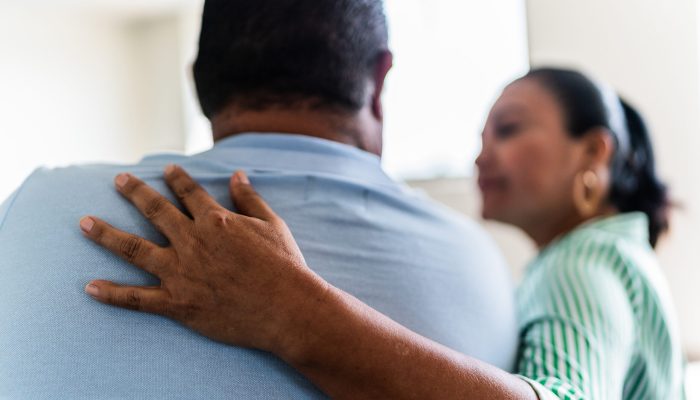 Man being comforted by his wife at home