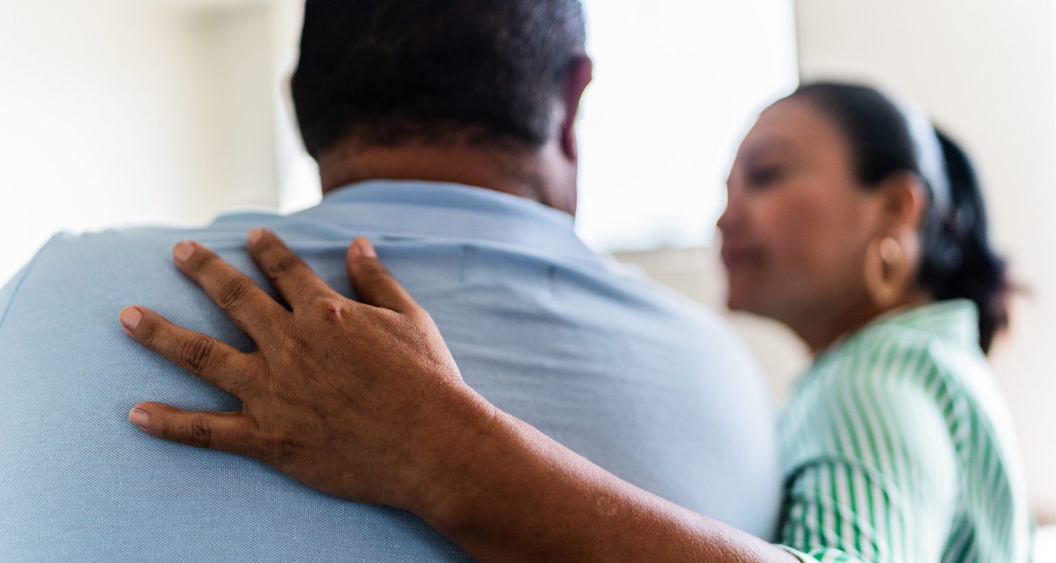 Man being comforted by his wife at home