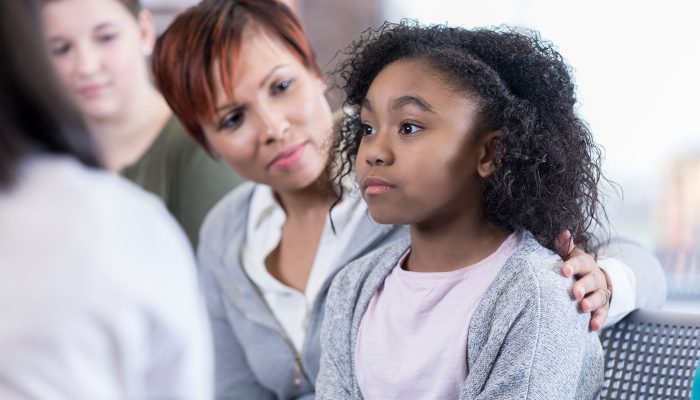 School counselor comforts elementary age student while in group therapy session.