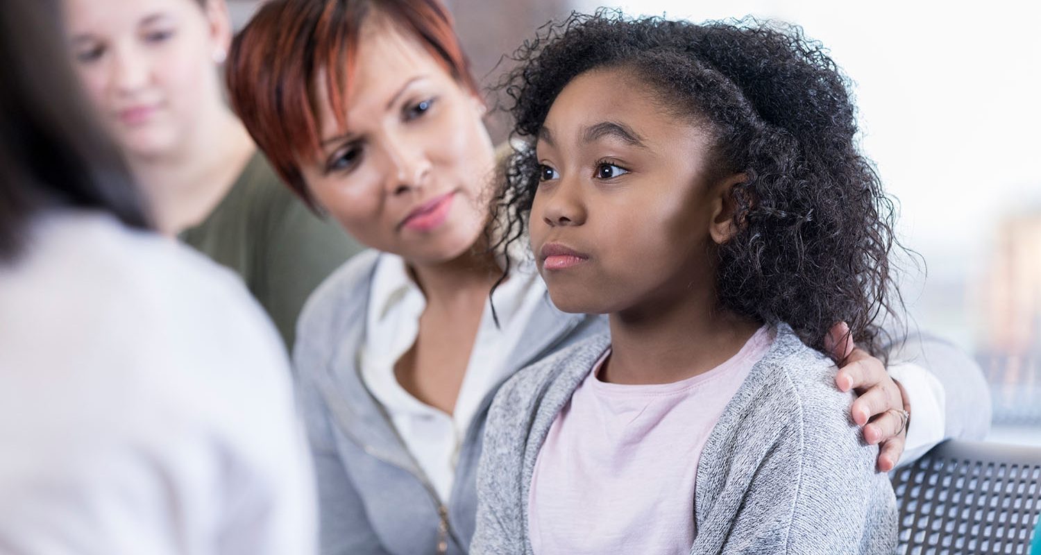 School counselor comforts elementary age student while in group therapy session.